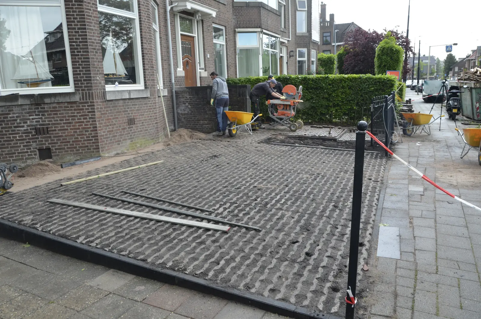 Het team aan het werk in de voortuin, met afzetlint langs de straat