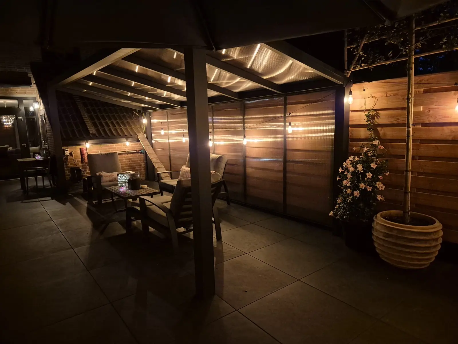 De veranda in de avond, met lichtsnoer en loungebank onder het dak — Rotterdam