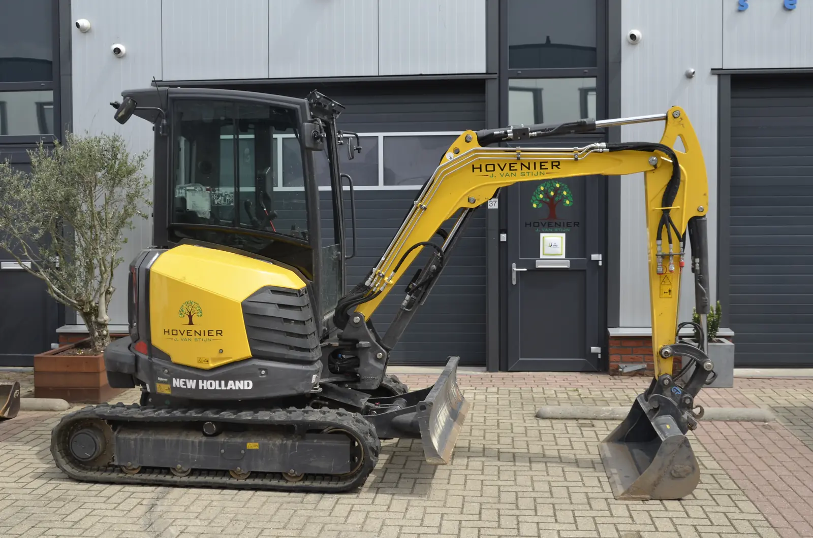 De New Holland in zijaanzicht, met de bak losgekoppeld ernaast