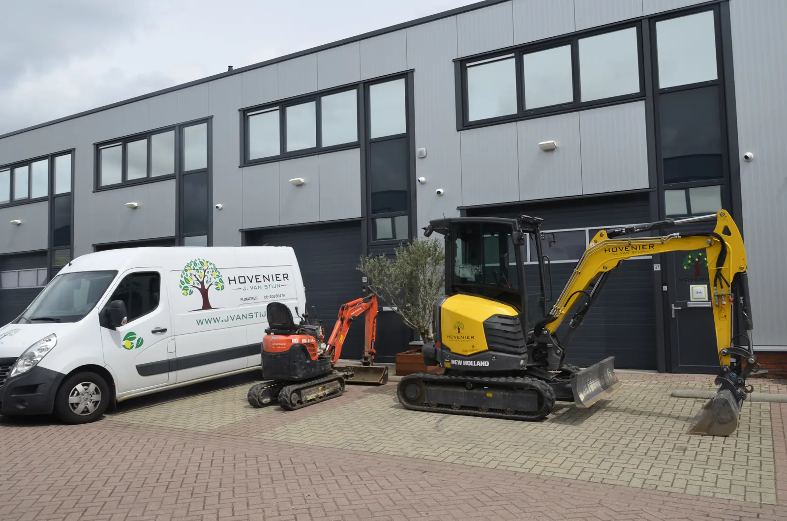 De bedrijfsbus met daarachter de minigraver en de grote graafmachine