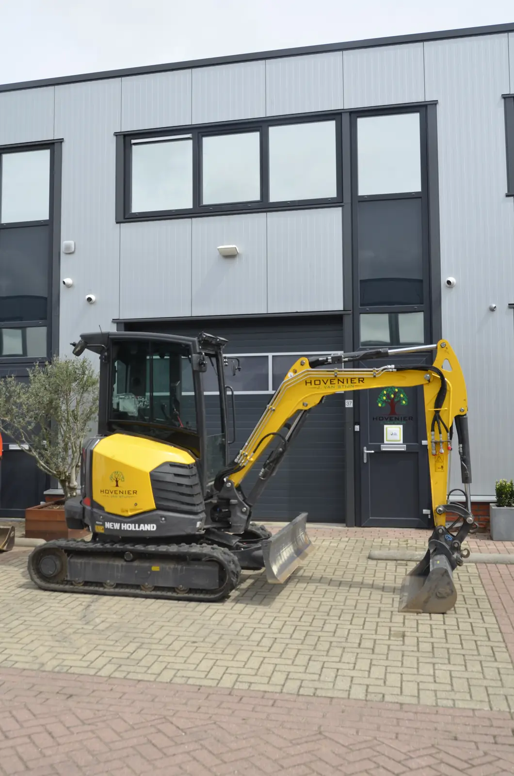De graafmachine op de klinkers voor ons pand, gereed om te laden