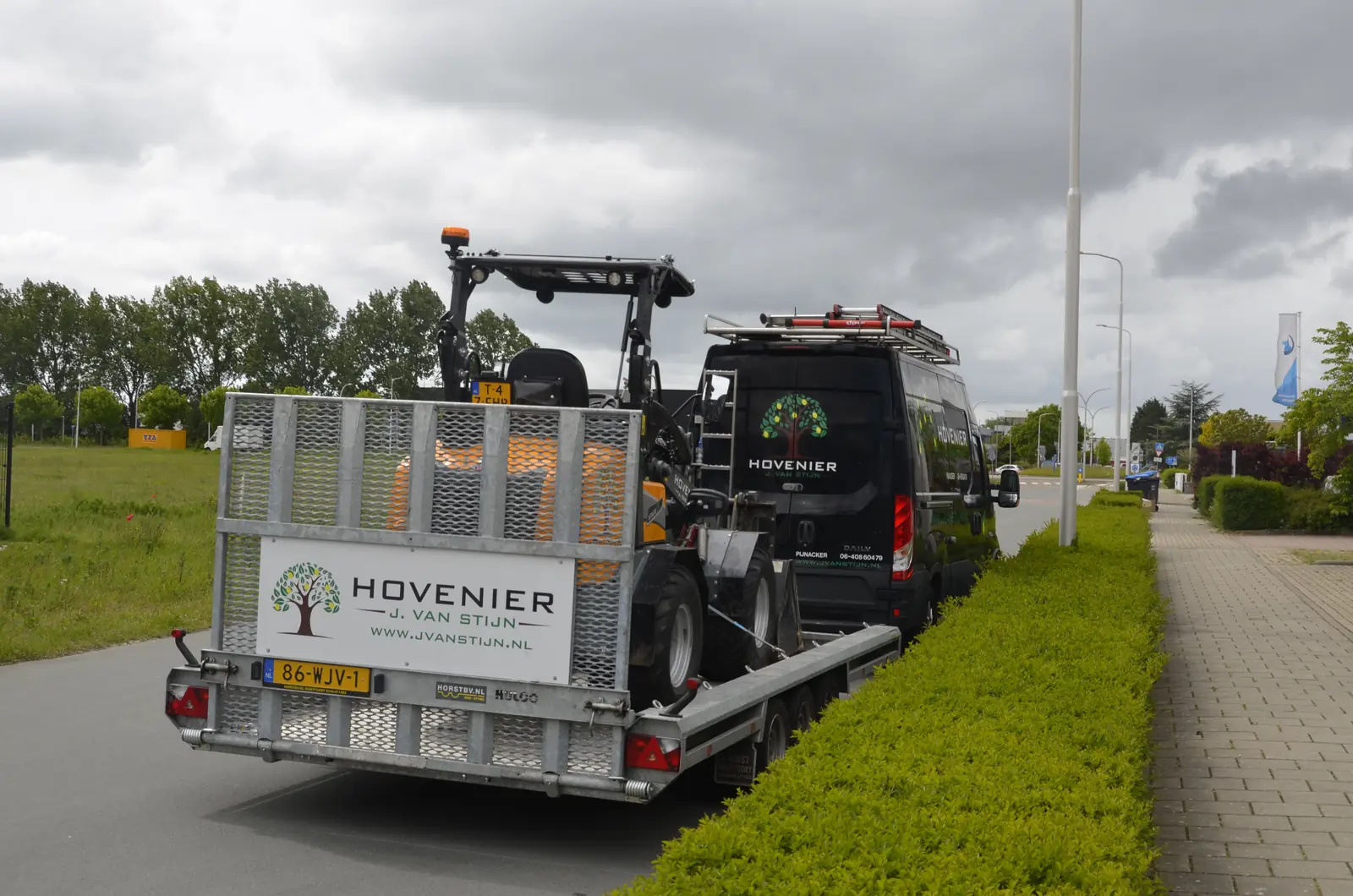 Aanhanger met de shovel erop, achter de bus op weg naar de stad