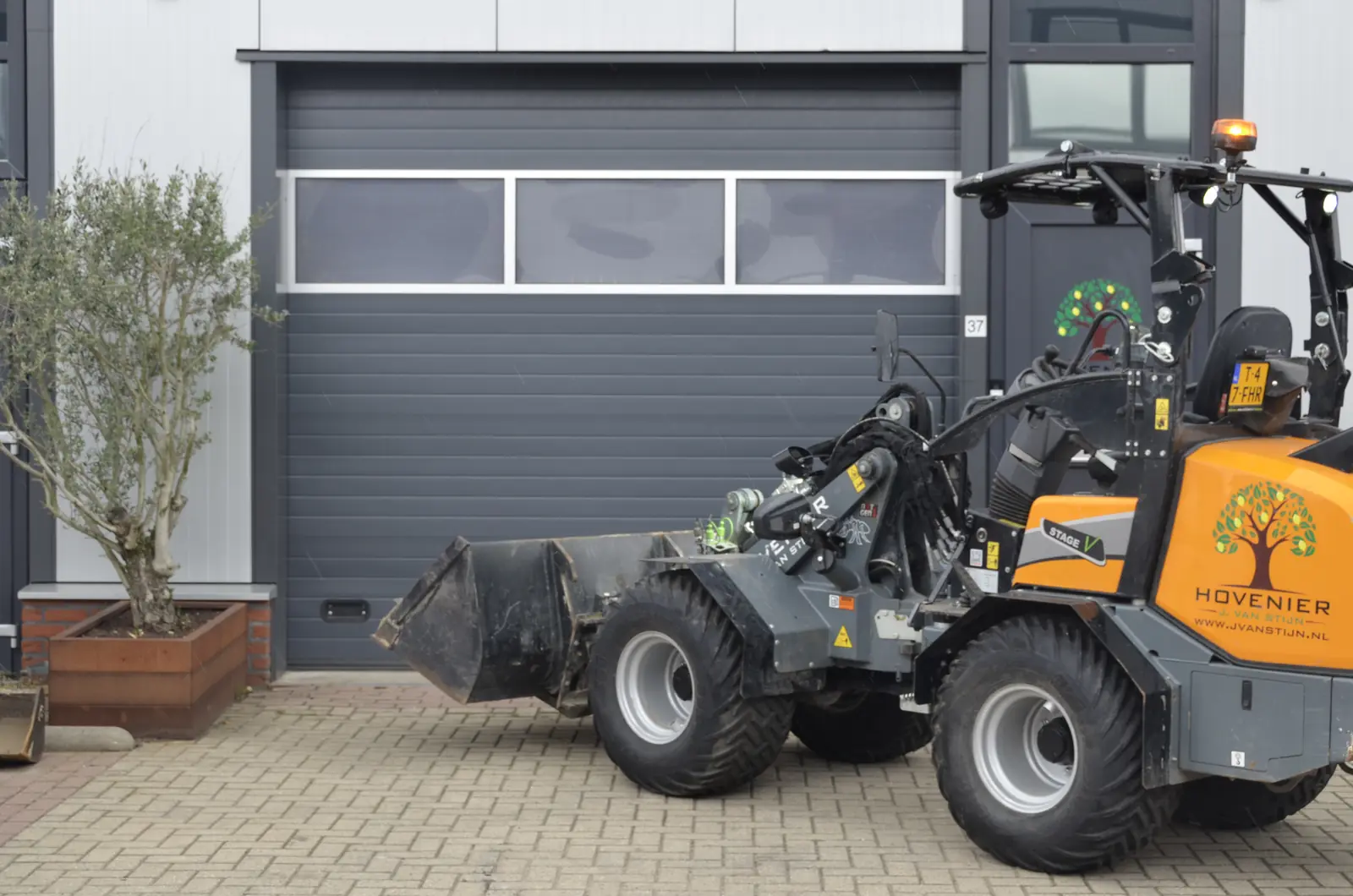 De shovel met bak, voor de garage van ons pand