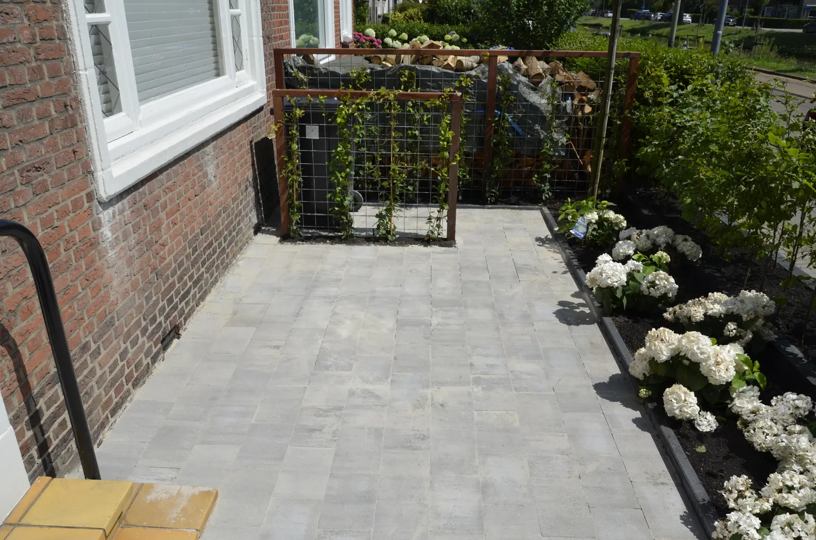 De voortuin in het geheel: bestrating, border en de haardhoutwand